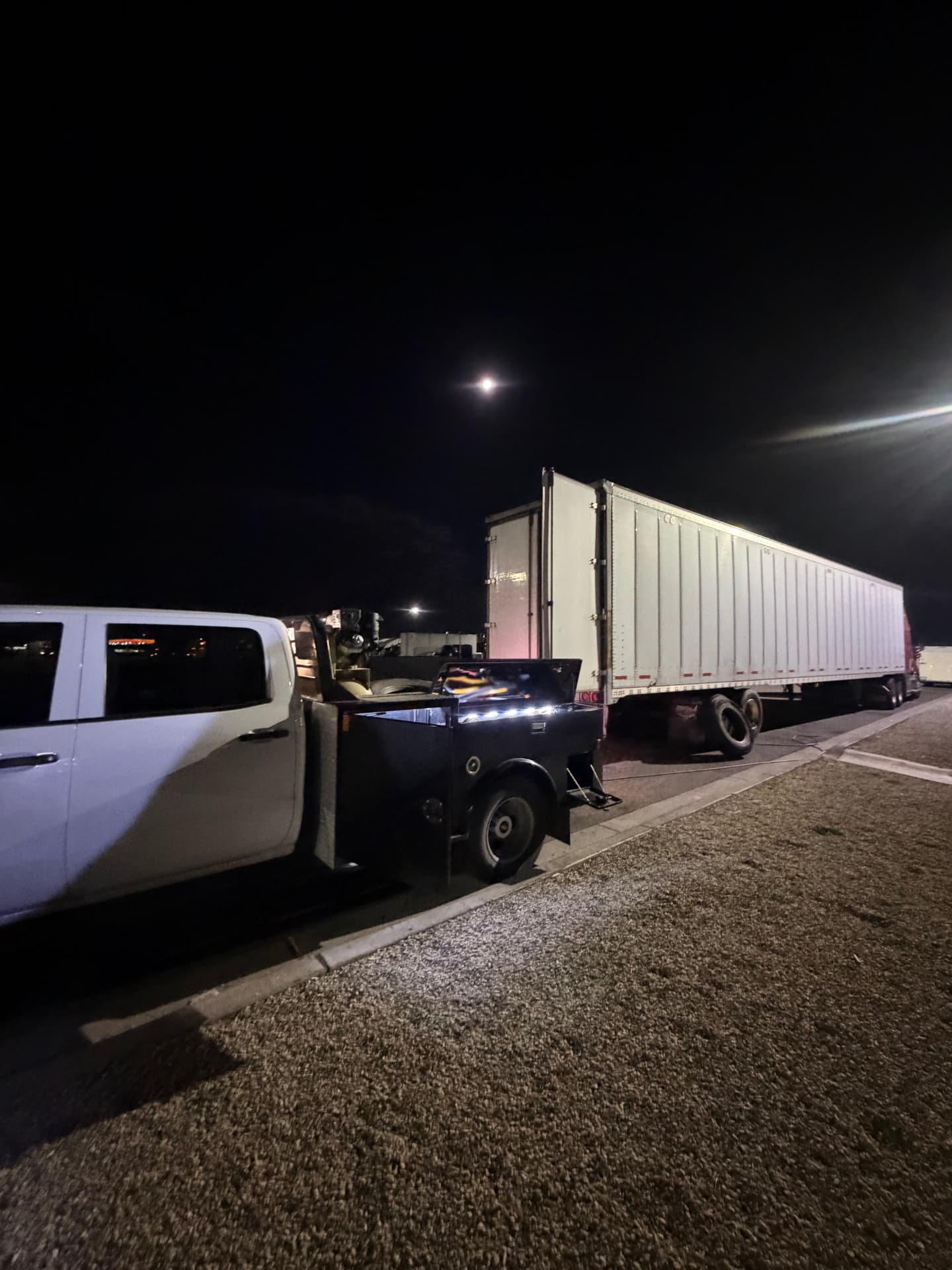 Mobile service truck parked next to a dry van trailer at night
